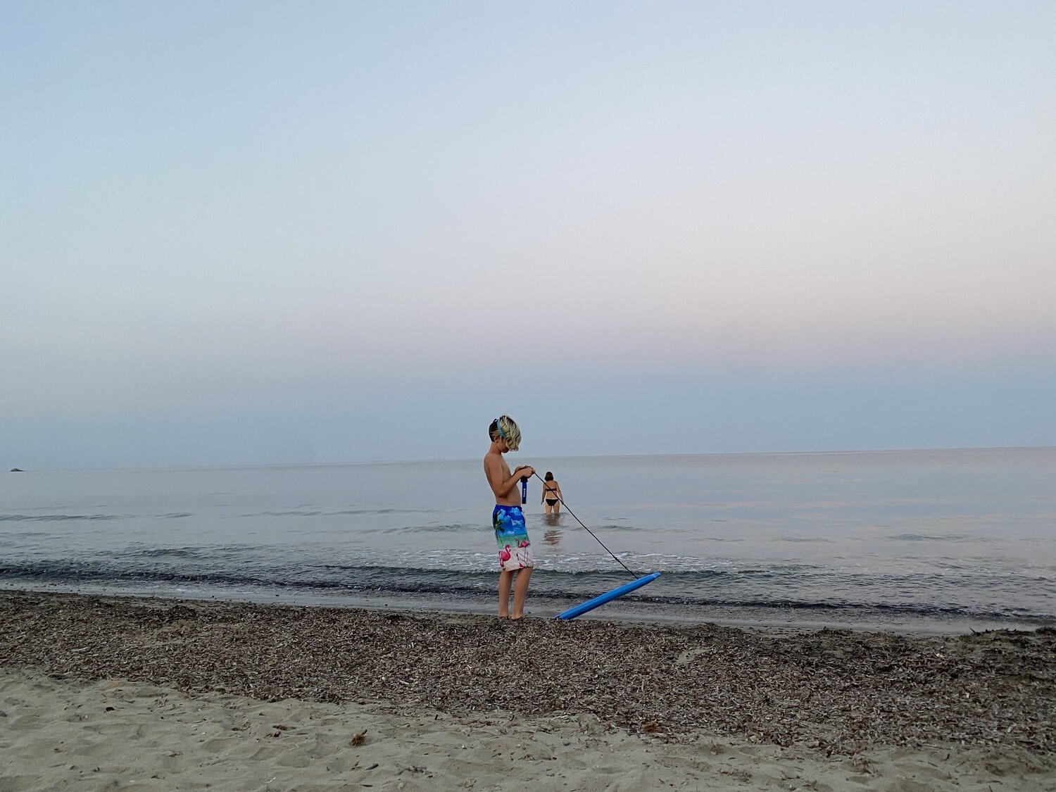 Boy skimboarding at sunset on the beach in Tertenia Sardinia