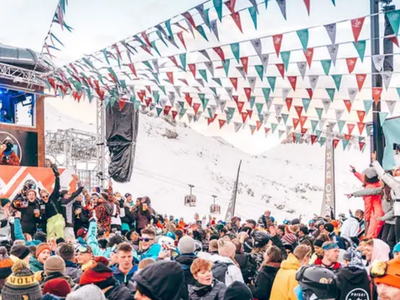 Après-ski scene in Les Deux Alpes, France, with a DJ playing music for a crowd of skiers.