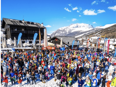Après-ski party in Livigno, Italy, with skiers gathered outdoors enjoying music and drinks in the snow.