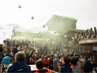 Crowd enjoying après-ski in Tignes, France, with a mix of music, drinks, and mountain views.