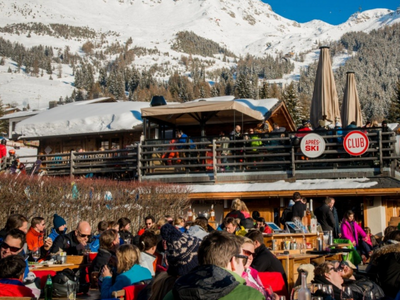 Après-ski in Verbier, Switzerland, featuring a stylish crowd enjoying drinks and music with stunning alpine views.