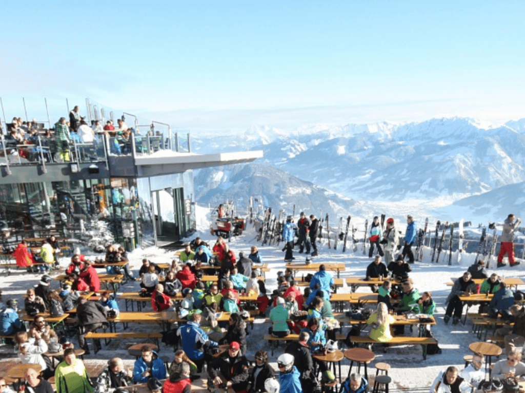 Lively après-ski scene in Zell am See, Austria, with skiers enjoying drinks and music after a day on the slopes.