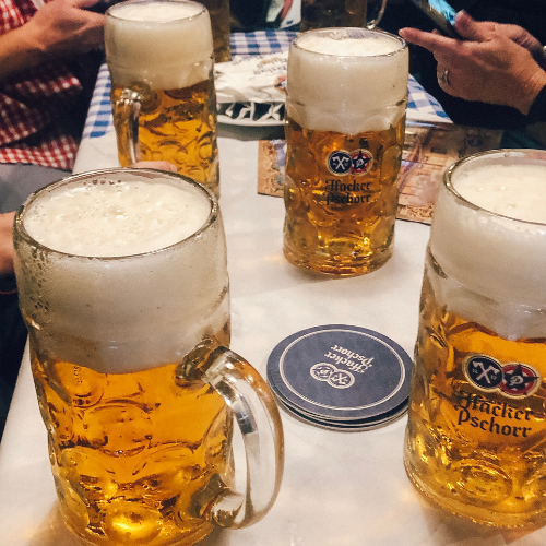 Four full steins of beer on a table at Oktoberfest in Munich