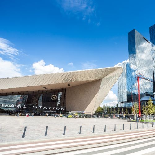Modern entrance of Rotterdam Centraal Station under a blue sky in Rotterdam, Netherlands.