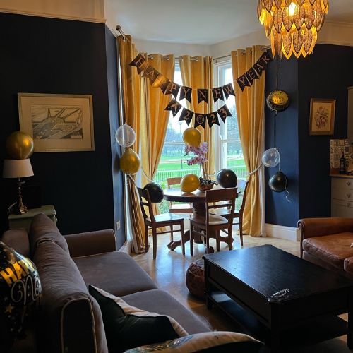 Airbnb living room in Gloucester decorated for New Year’s Eve with balloons and a banner.