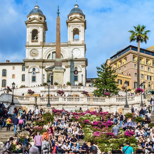 Spanish Steps in Rome with blooming flowers and people gathered in the square