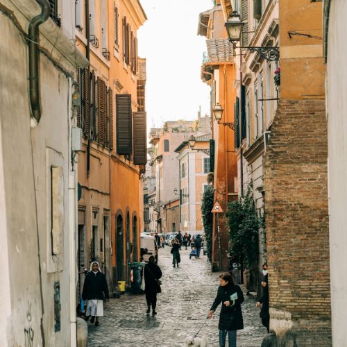 Trastevere narrow cobblestone street with people walking in Rome