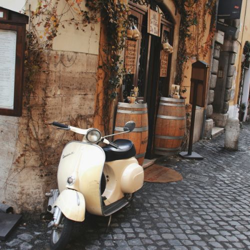 Cream-colored Vespa parked in front of a wine bar in Trastevere