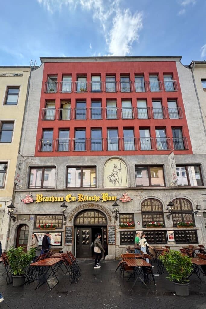 Exterior of Brauhaus Em Kölsche Boor on Eigelstein, Cologne, with outdoor tables and traditional painted signage