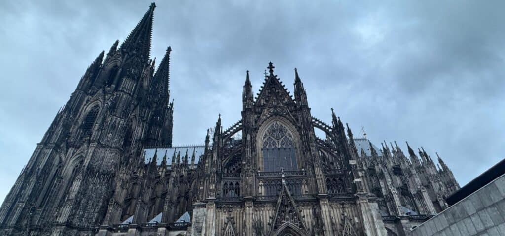 Looking up at the Gothic facade of Cologne Cathedral (Kölner Dom) against a dramatic sky