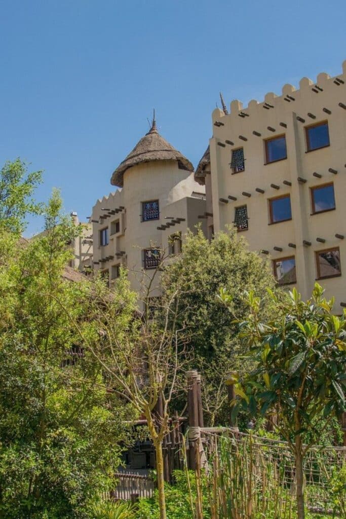 The exterior of Hotel Matamba at Phantasialand, an Africa-themed on-site hotel surrounded by lush tropical vegetation and thatched roof structures
