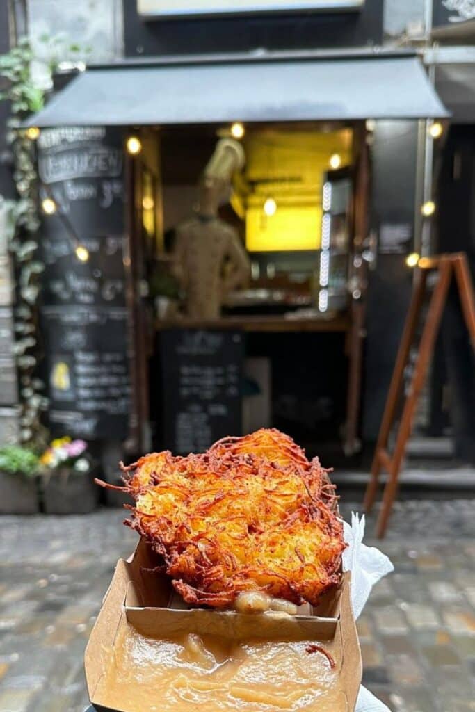 A freshly fried reibekuchen potato pancake in a box outside the Rievkoochebud window in Cologne