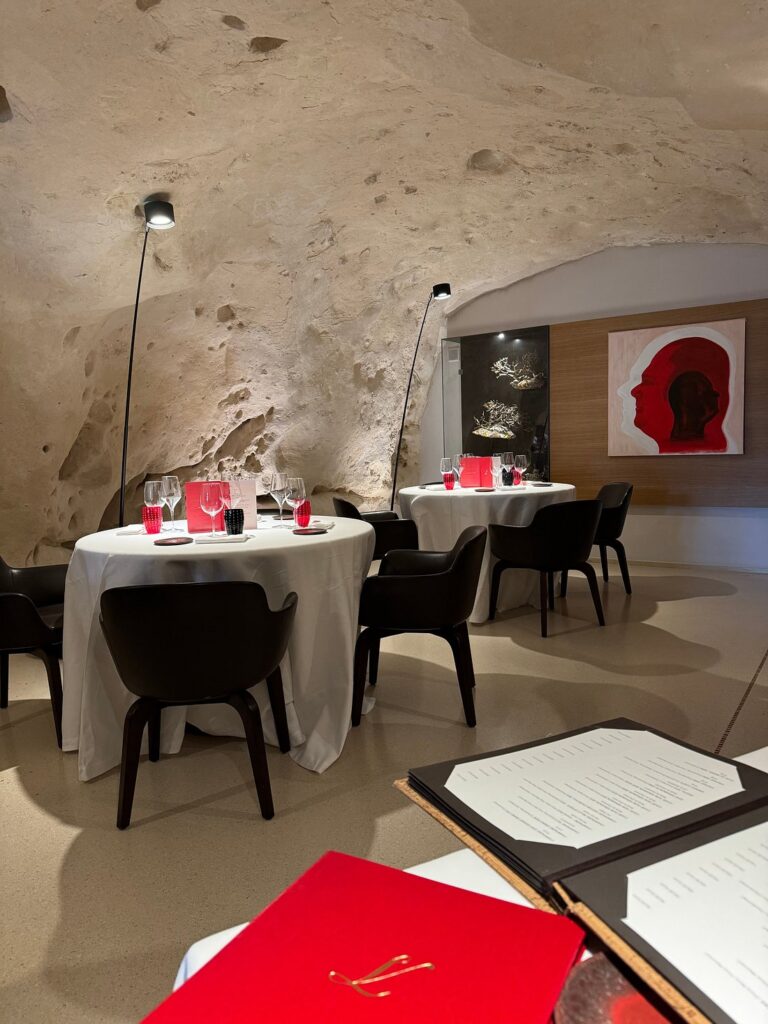 Elegant cave dining room at Vitantonio Lombardo, Matera's only Michelin-starred restaurant, with white tablecloths and vaulted stone ceiling