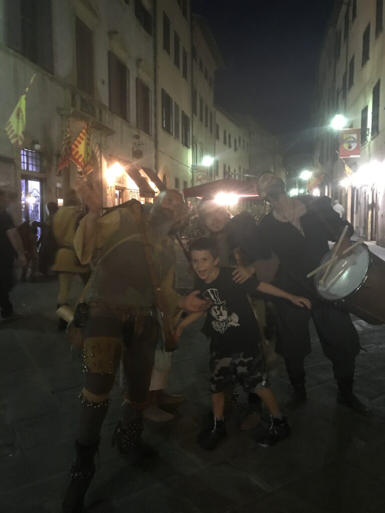 Torchlit night parade through Volterra's streets during the AD 1398 festival