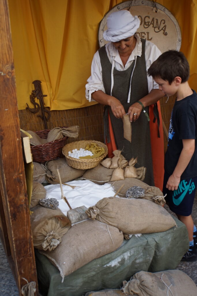 Grinding salt by hand at the Bottega del Sale stall during Volterra AD 1398
