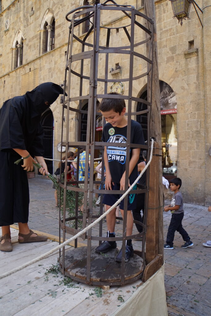 A child locked in a costumed iron cage display in Volterra's main square