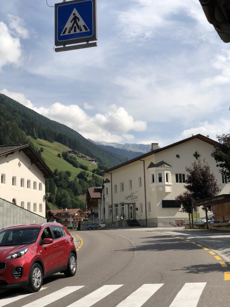 Car on a road through a mountain village in the Dolomites