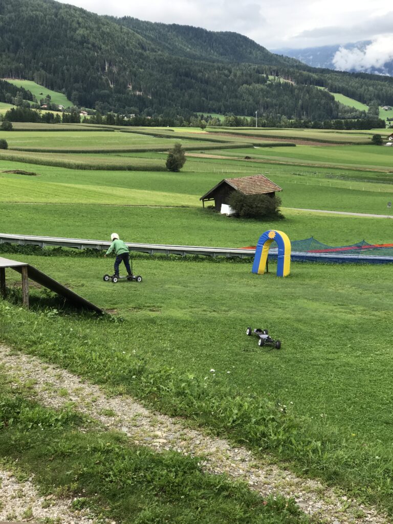 Child riding a mountain cart through the green countryside of the Dolomites