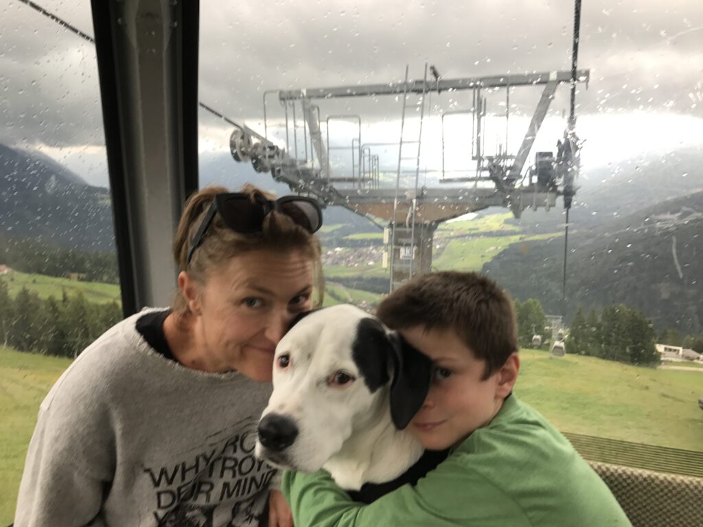 Family riding a mountain gondola with their dog in the Dolomites