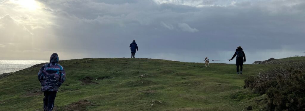 Group walking with a dog along the coast near Three Cliffs Bay in South Wales