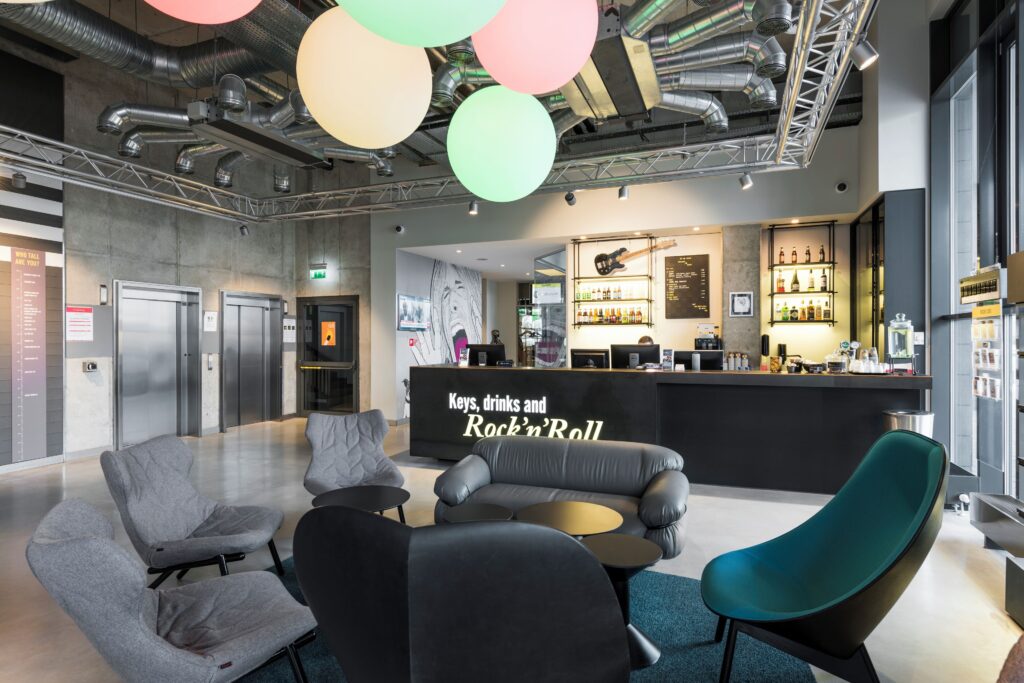 Modern lobby at Comfort Hotel LT Vilnius with colorful ceiling lights, lounge seating and a rock-and-roll-themed reception desk.
