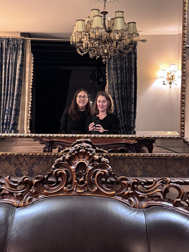 Ornate mirror, antique furnishings and two travelers inside a historic apartment in Vilnius Old Town