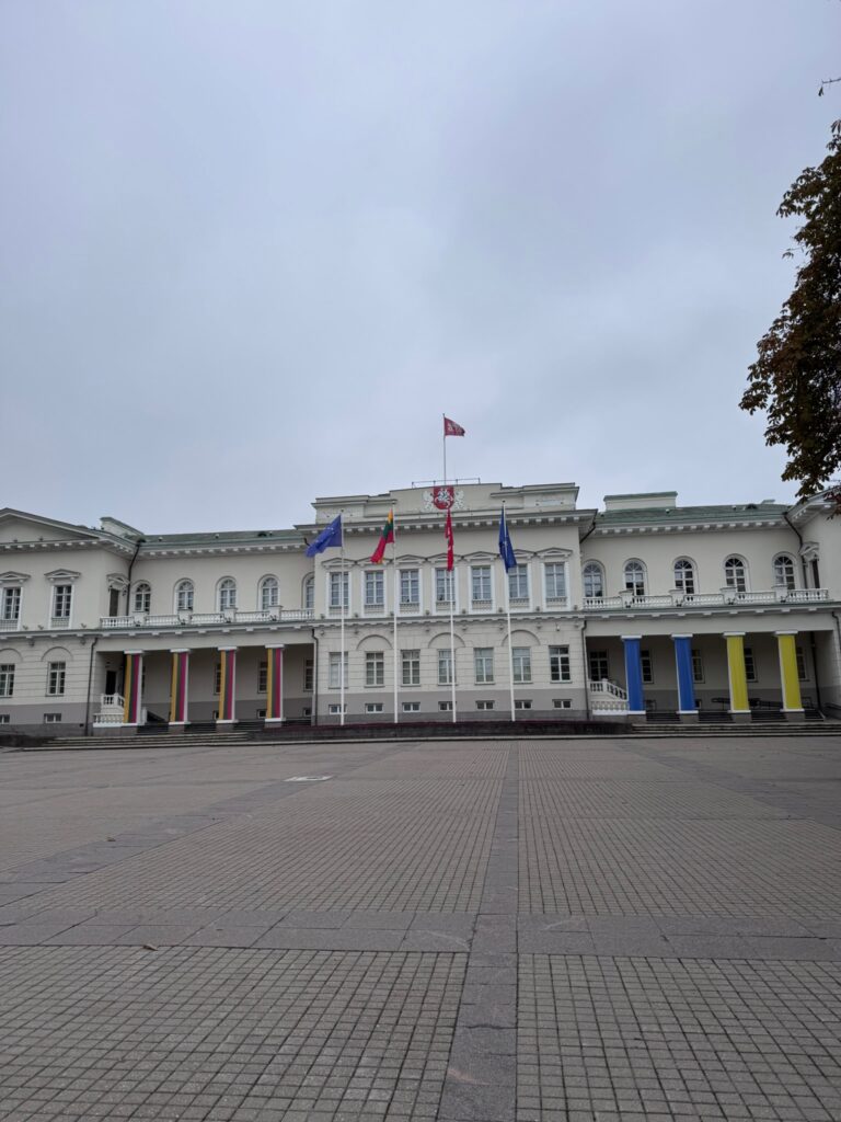 White neoclassical Presidential Palace in Vilnius with Lithuanian and European flags displayed outside