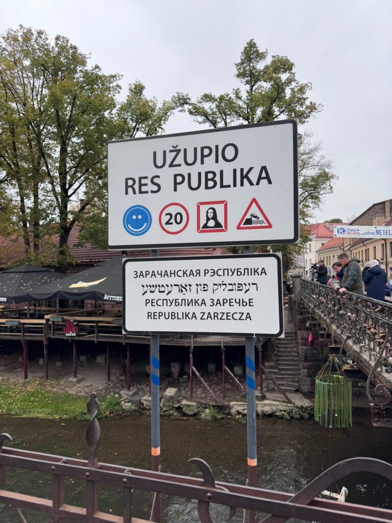Republic of Užupis welcome sign beside the Vilnelė River and bridge in Vilnius