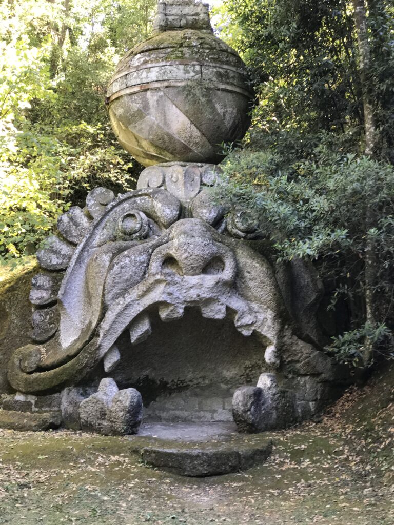 Large stone monster sculpture topped with a globe at the Garden of Monsters in Bomarzo
