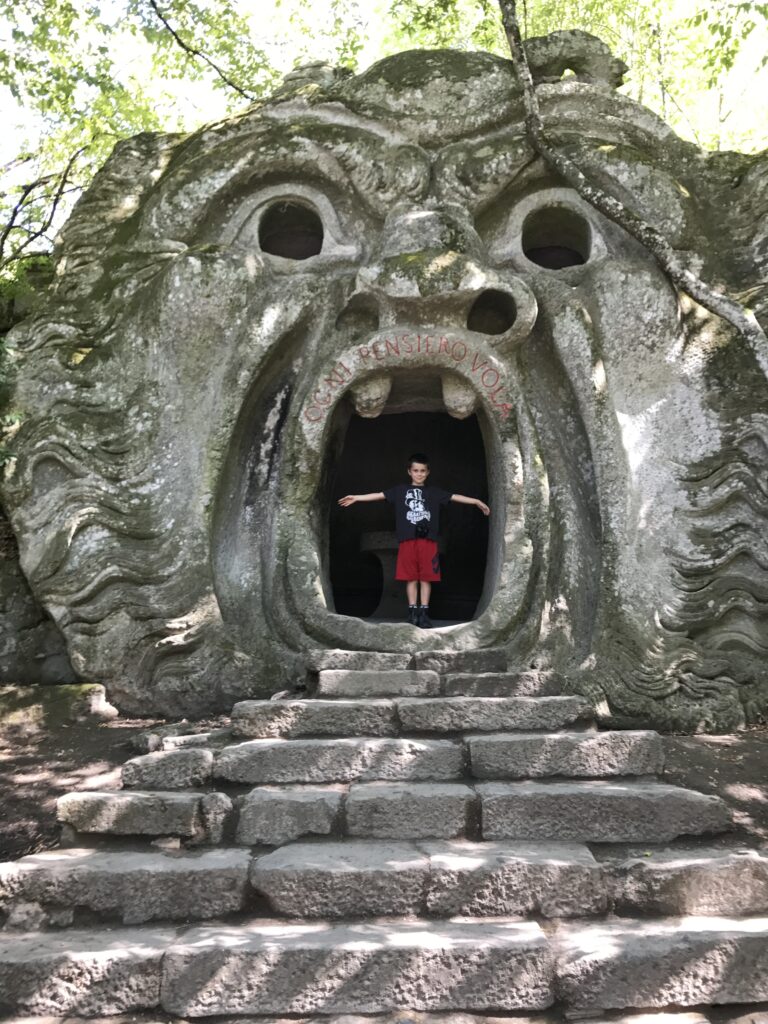 Giant stone Mouth of Orcus sculpture at the Garden of Monsters in Bomarzo with a child standing inside
