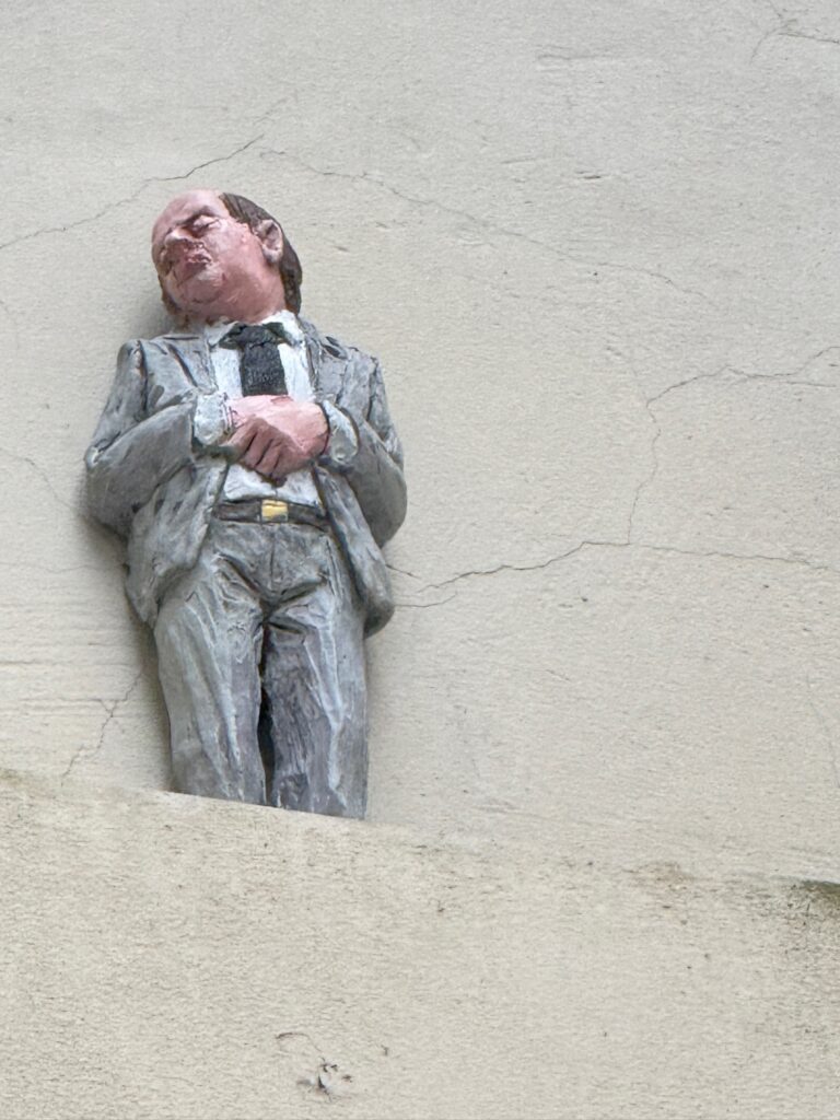 Small sculpture of a businessman in a gray suit set into the exterior wall of a building in Vilnius