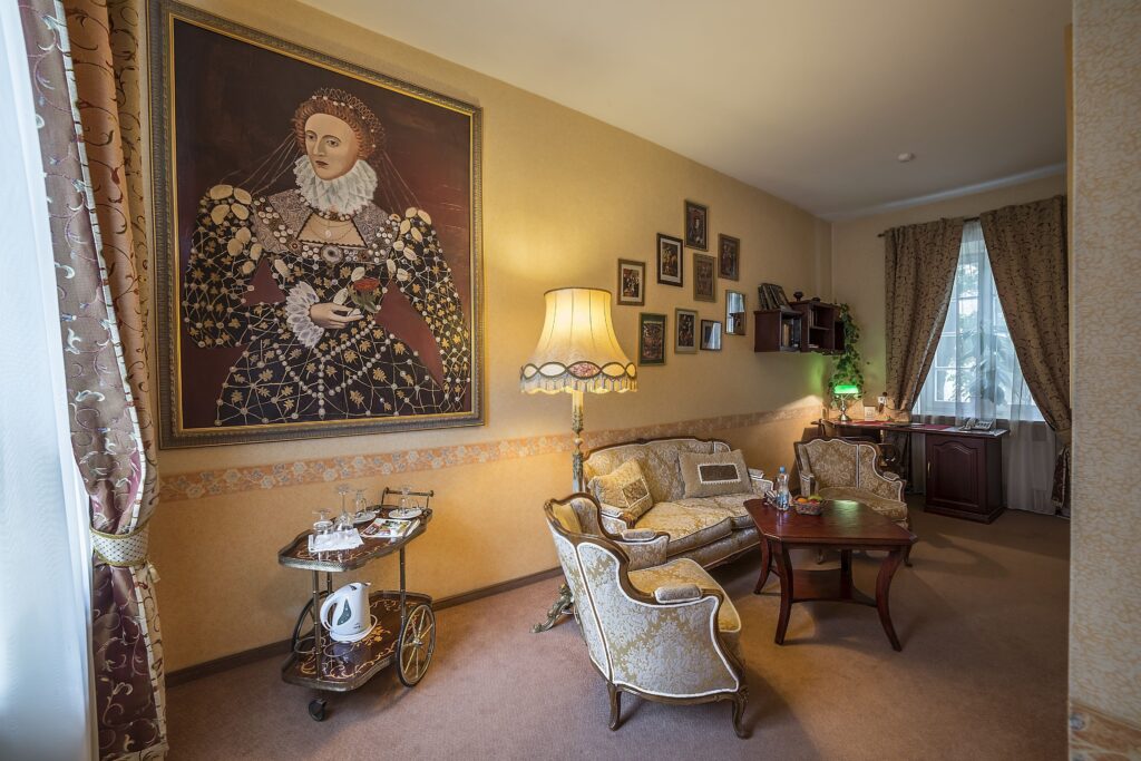 Elegant guest room at Shakespeare Boutique Hotel in Vilnius with antique-style furniture, a large portrait and traditional decor.