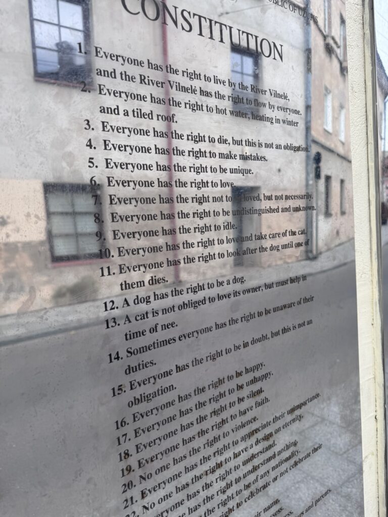 English-language Užupis Constitution displayed on a wall, including articles about the rights of dogs and cats